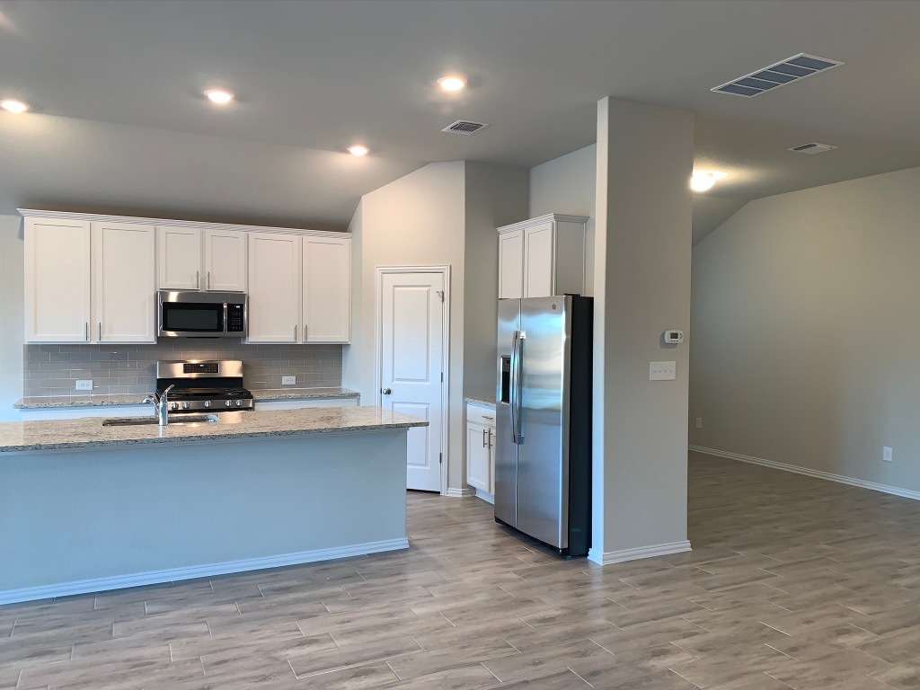 265 Falling Star Lane Georgetown, TX 78628 - Photo 3 of 22 a kitchen with stainless steel appliances a refrigerator sink and microwave