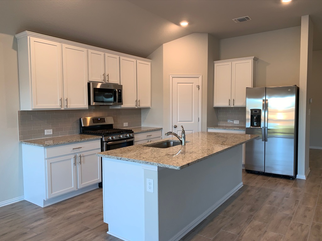 265 Falling Star Lane Georgetown, TX 78628 - Photo 4 of 22 a kitchen with stainless steel appliances granite countertop a sink a stove a refrigerator a microwave and cabinets