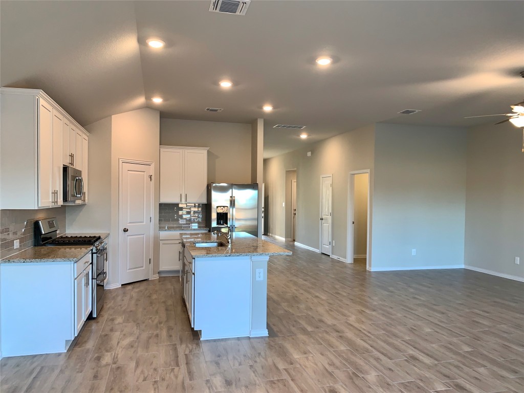 265 Falling Star Lane Georgetown, TX 78628 - Photo 5 of 22 a view of a kitchen with kitchen island a sink wooden floor and a counter top space