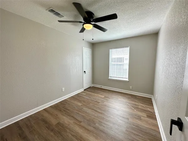an empty room with wooden floor ceiling fan and windows