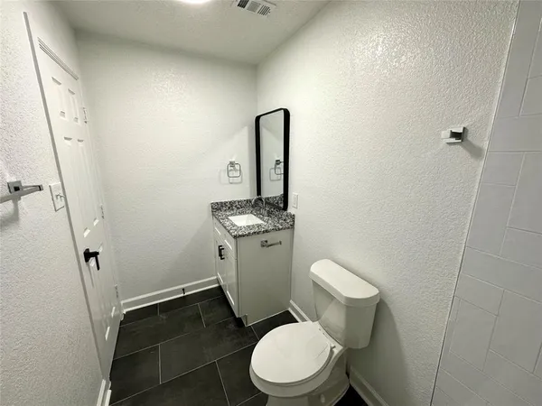 a white toilet sitting next to a bathroom sink and a mirror