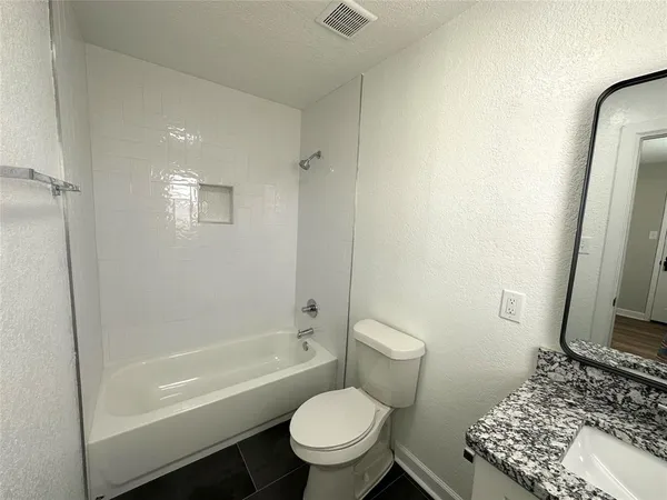 a bathroom with a granite countertop toilet a sink and bathtub