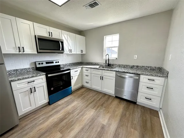 a kitchen with granite countertop a sink cabinets stainless steel appliances and a counter space