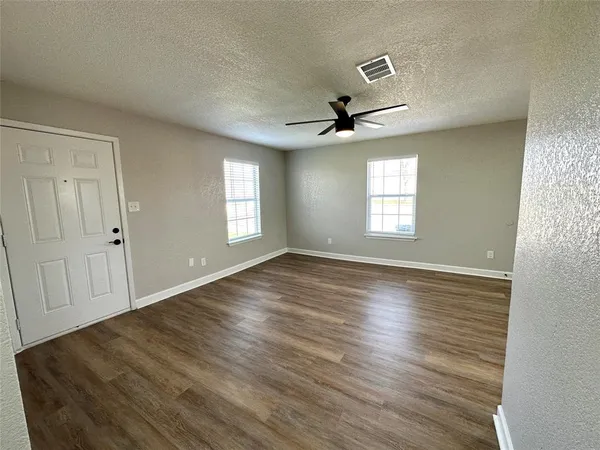 an empty room with wooden floor and windows