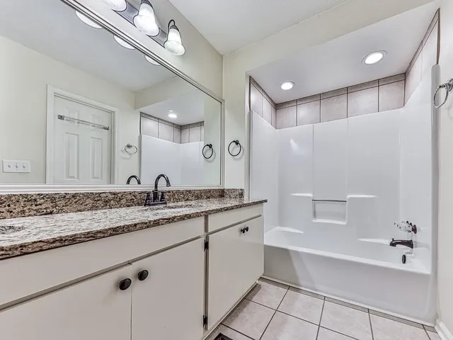 a bathroom with a granite countertop sink mirror and bathtub