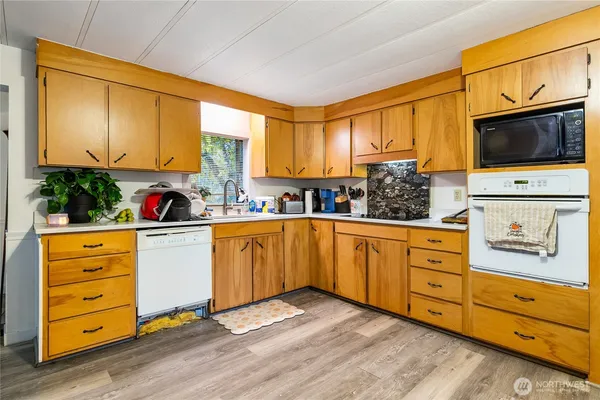 a kitchen with stainless steel appliances granite countertop a stove a sink and a refrigerator with wooden floors