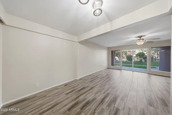 a view of an empty room with wooden floor and a window