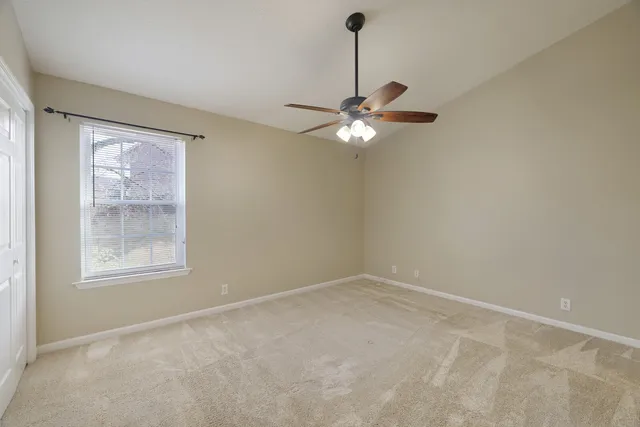 an empty room with chandelier fan and window