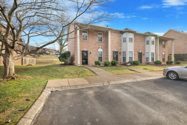 a view of a white house with a big yard and large trees