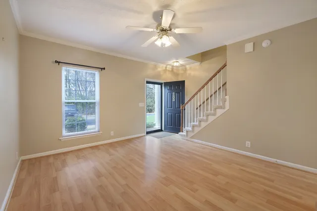 a view of an empty room with window and wooden floor