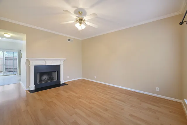 an empty room with a fireplace and chandelier fan