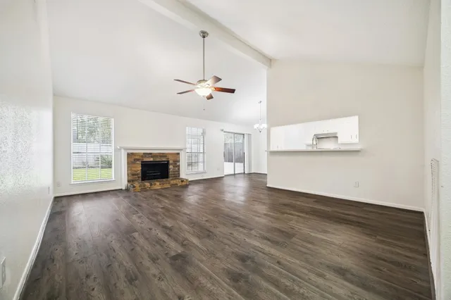 an empty room with wooden floor fireplace and windows