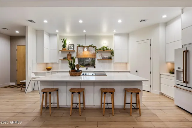 a large kitchen with stainless steel appliances a white stove top oven a sink a dining table and chairs