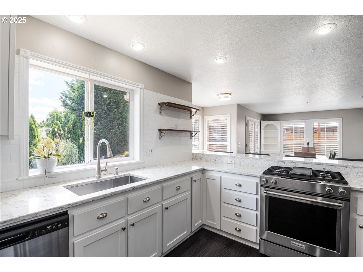 3253 Southeast 24th Terrace Gresham, OR 97080 - Photo 12 of 43 a kitchen with granite countertop white cabinets appliances a large window and a sink
