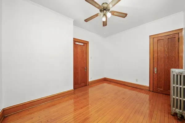 an empty room with wooden floor closet and fan