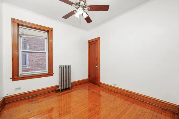 an empty room with wooden floor fan and windows