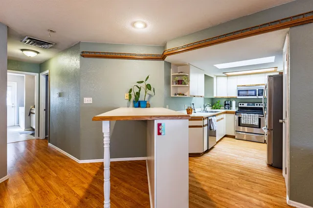 a kitchen with stainless steel appliances kitchen island granite countertop a refrigerator and a sink