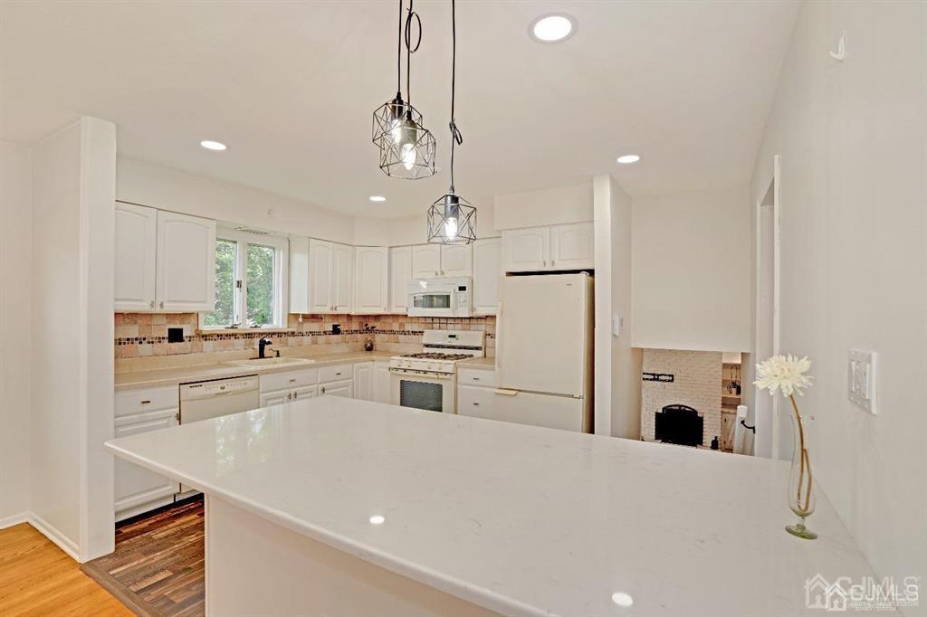 63 South Cliff Road Colonia, NJ 07067 - Photo 8 of 37 a kitchen with kitchen island a stove a refrigerator a sink and white cabinets with wooden floor