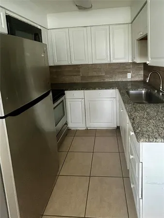 a kitchen with a refrigerator a sink and white cabinets