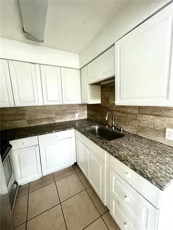 a kitchen with granite countertop a sink a stove and cabinets