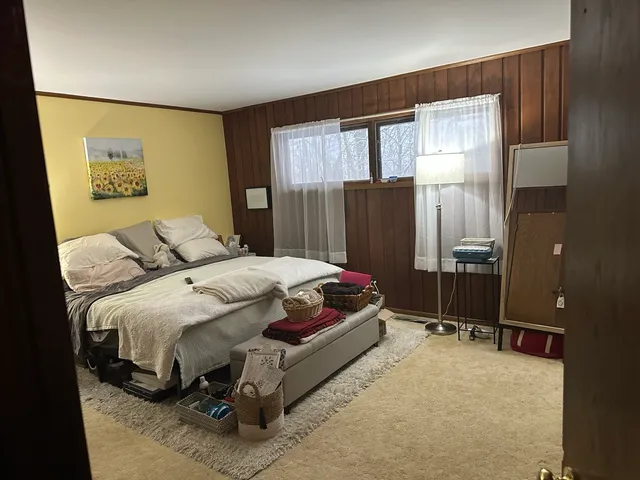 a bedroom with a bed dresser and a large window