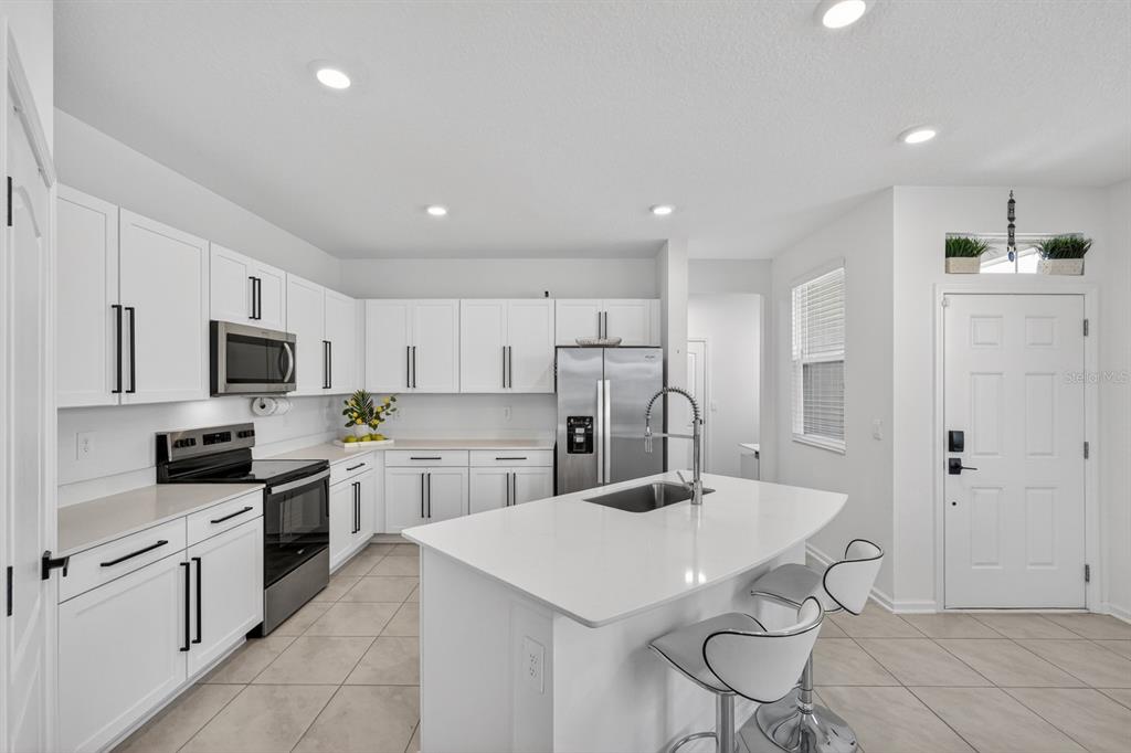 336 Redbud Road Palm Coast, FL 32137 - Photo 7 of 40 a kitchen with stainless steel appliances a sink a stove a refrigerator cabinets and a dining table