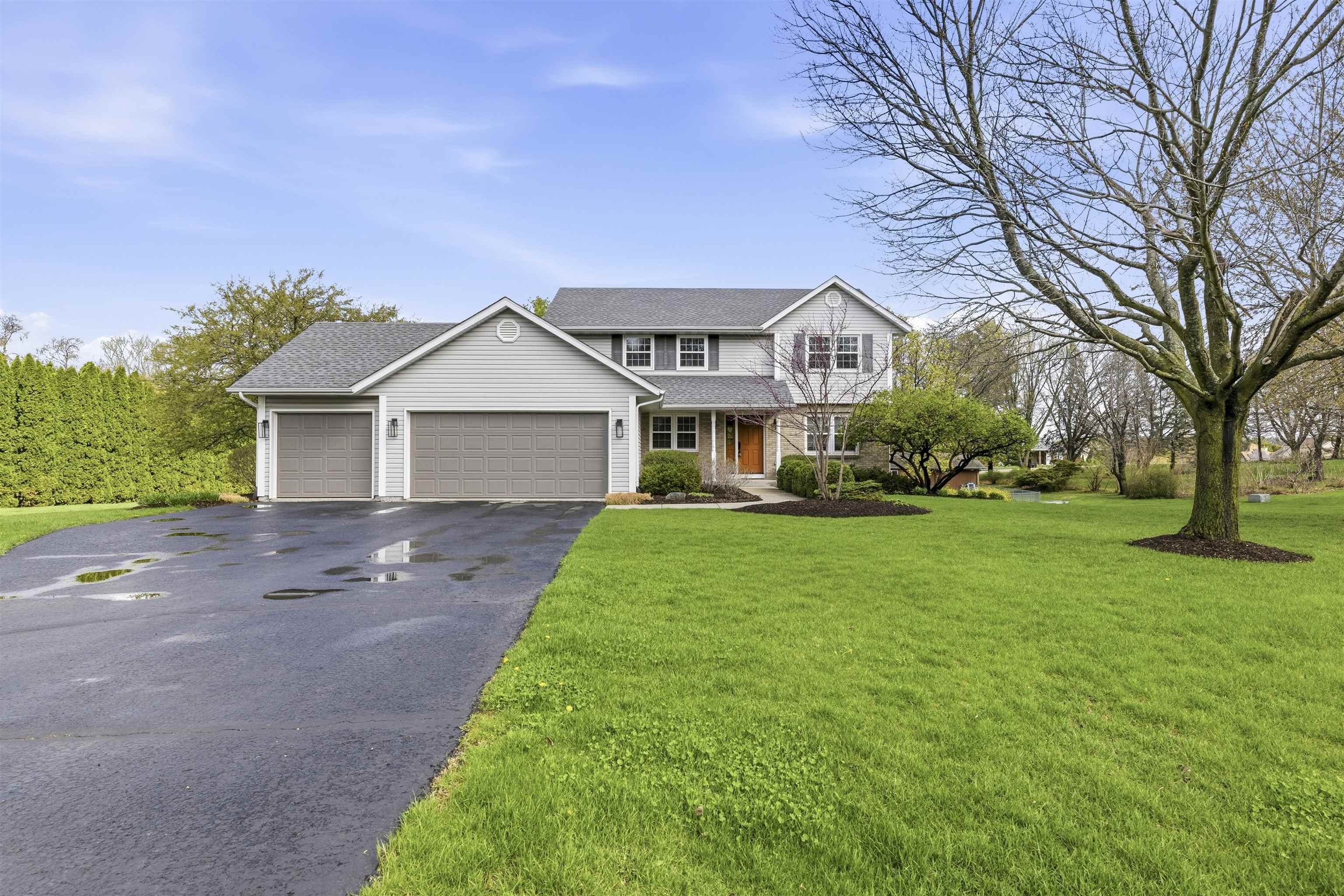 6990 Skyview Trail Roscoe, IL 61073 - Photo 1 of 43 a front view of a house with a garden and trees