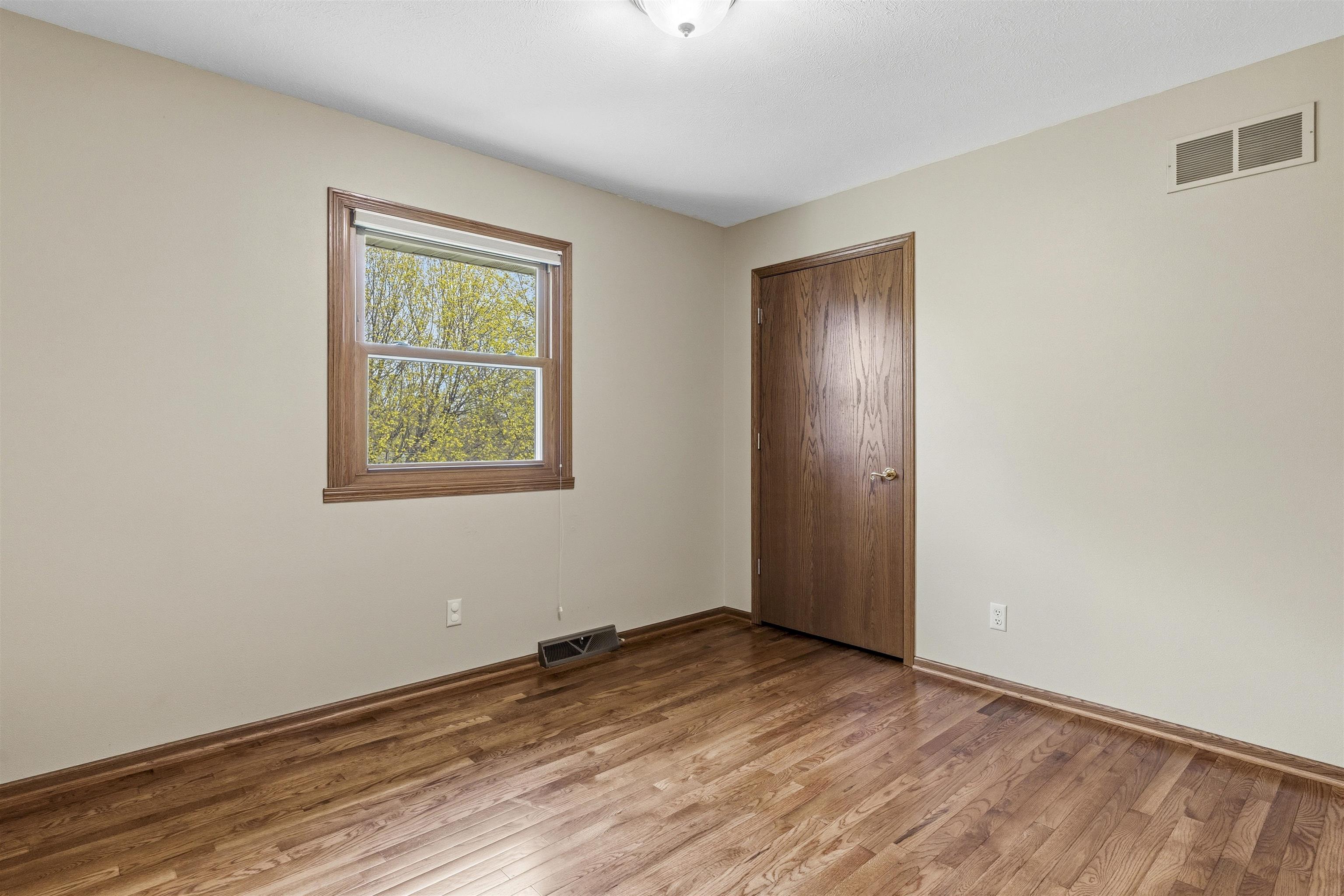 6990 Skyview Trail Roscoe, IL 61073 - Photo 24 of 43 an empty room with wooden floor and windows
