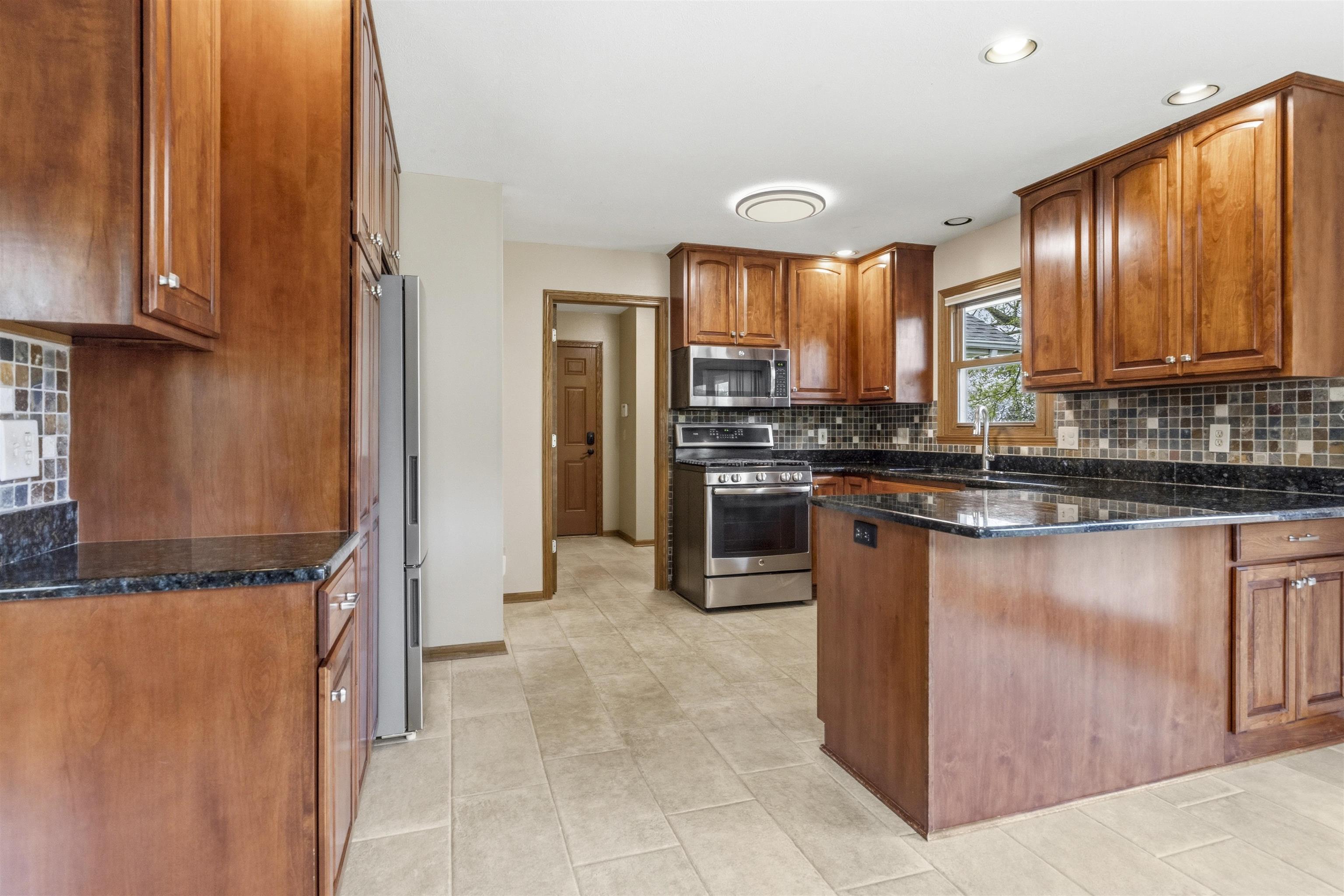 6990 Skyview Trail Roscoe, IL 61073 - Photo 4 of 43 a kitchen with stainless steel appliances granite countertop a stove a sink and a refrigerator