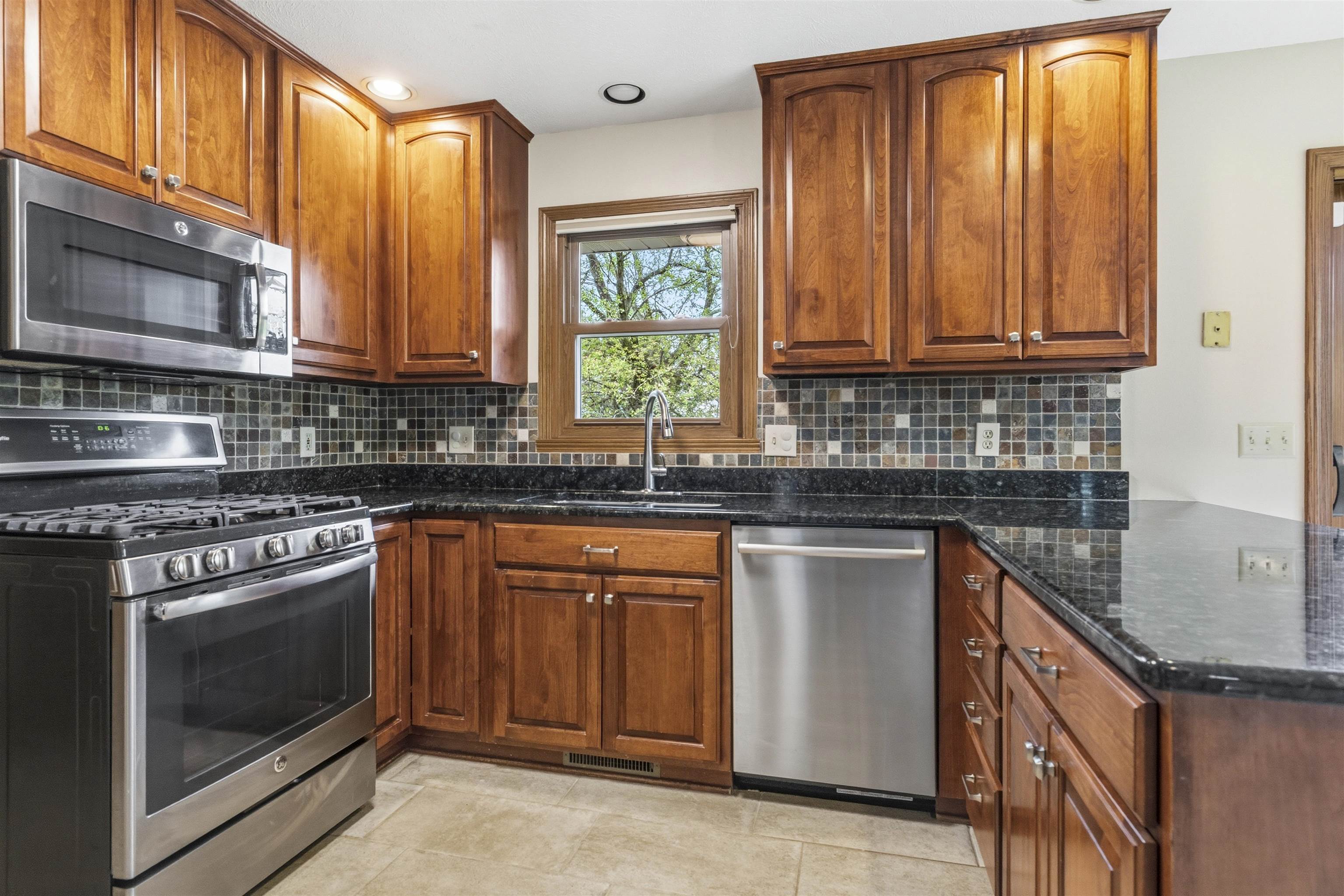 6990 Skyview Trail Roscoe, IL 61073 - Photo 5 of 43 a kitchen with stainless steel appliances granite countertop a stove a sink and a microwave