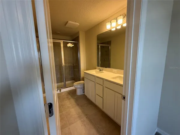 a bathroom with a double vanity sink toilet mirror and shower
