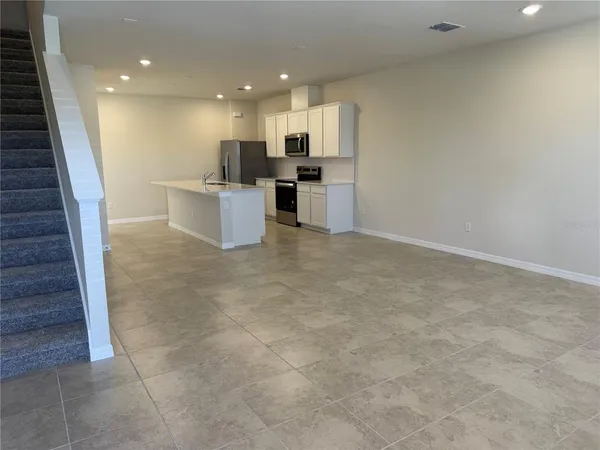 a view of kitchen with kitchen island stainless steel appliances cabinets a sink and a counter top space
