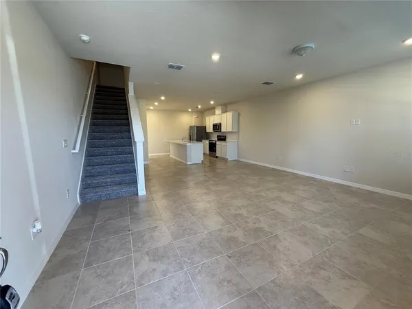 an empty room with wooden floor and a kitchen