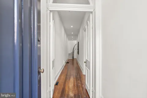 a view of a hallway with wooden floor and stairs
