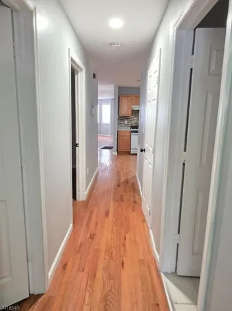 a view of a hallway with wooden floor and a bathroom