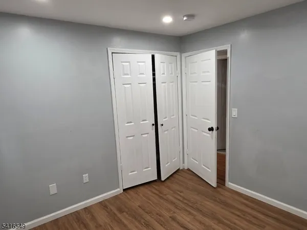 an empty room with wooden floor and closet area