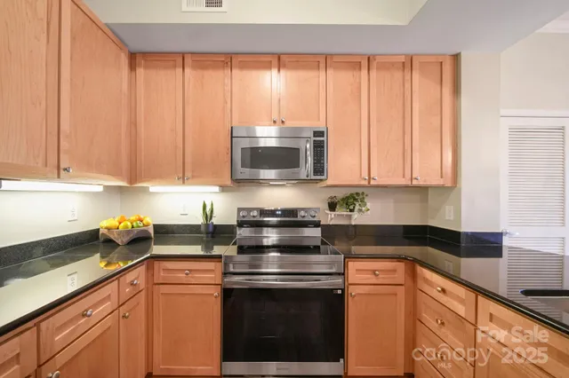 a kitchen with stainless steel appliances granite countertop white cabinets and a stove top oven with granite countertops