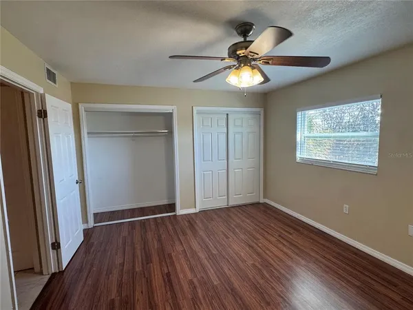 a view of empty room with wooden floor and fan