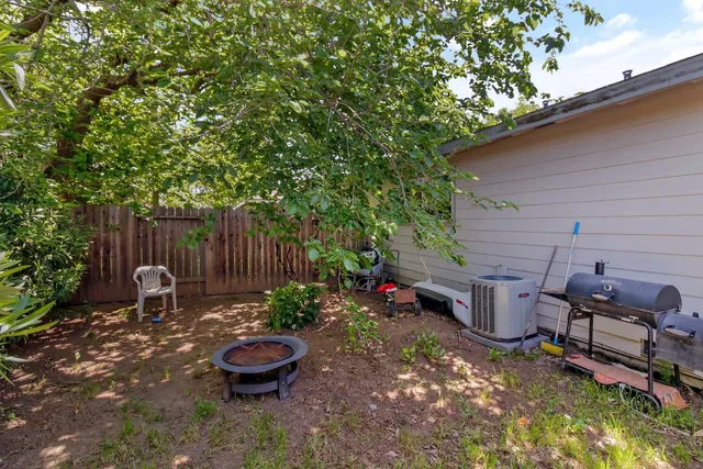 a backyard of a house with table and chairs under an umbrella