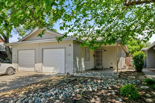 a front view of house with yard and trees in the background