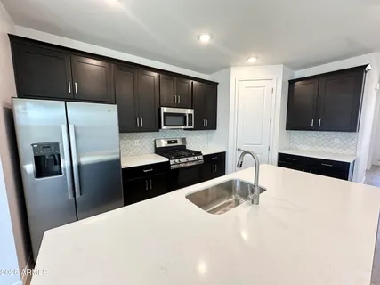 a kitchen with stainless steel appliances a refrigerator a sink a stove a microwave and wooden cabinets