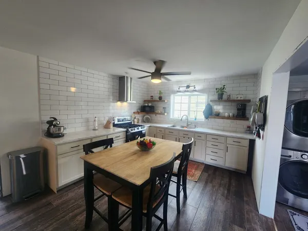 a kitchen with a table chairs a sink dishwasher stove and cabinets with wooden floor