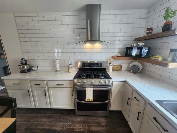 a kitchen with stainless steel appliances granite countertop a stove and white cabinets