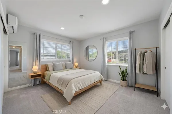 a bedroom with a bed a dresser and large window