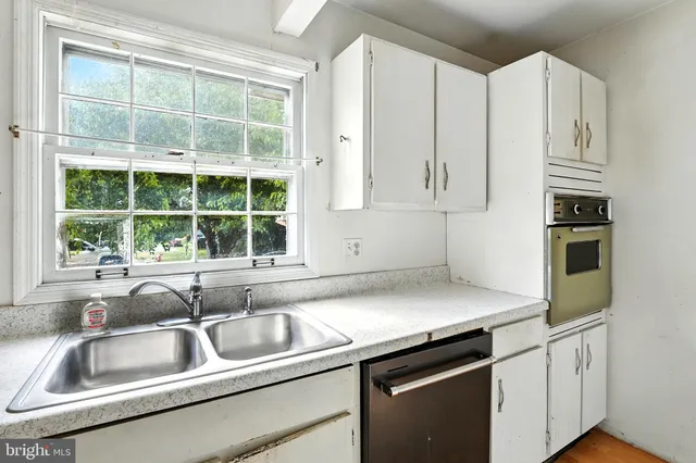 a kitchen with granite countertop a sink and white cabinets