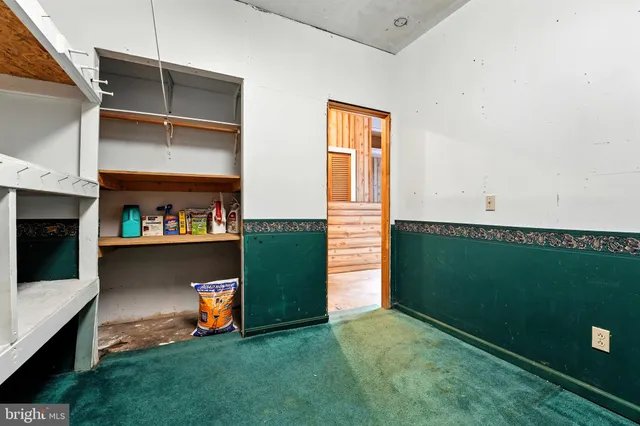 a view of an empty room with kitchen and a window