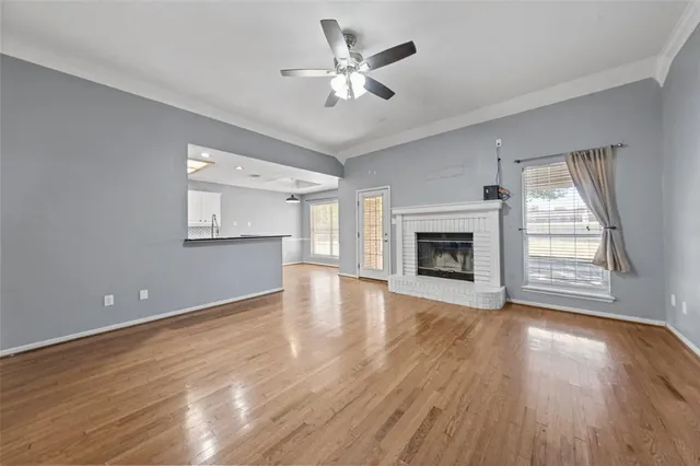 an empty room with wooden floor fireplace and windows