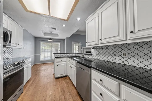 a kitchen with granite countertop a sink a stove oven and white cabinets