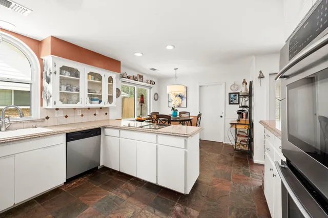 a large white kitchen with a sink and dishwasher a stove top oven with wooden floor