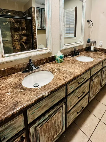 a bathroom with granite countertop double vanity and a window